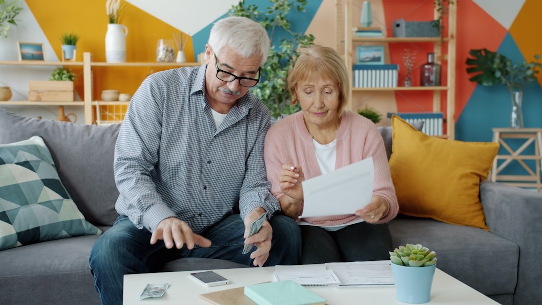 Happy family elderly man and woman are paying bills counting money then doing high-five and laughing enjoying extra cash. People and finance concept.
